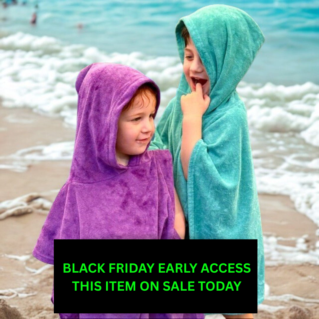 Two children in hooded towels on a beach with a Black Friday sale text overlay.